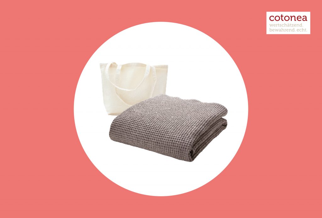 Ein braunes gefaltetes Handtuch aus Baumwolle vor einer naturfarbenen Baumwolltasche